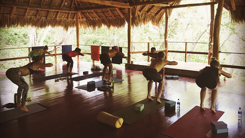 Gente practicando yoga en una cabaña exterior