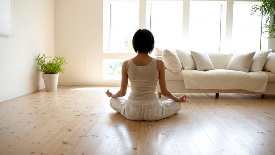 Mujer practicando yoga en casa junto a sofa y cactus